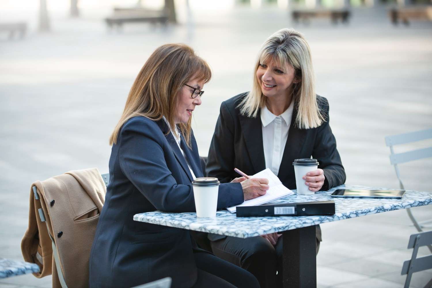 Immigration attorney services - two professionals collaborating on legal documents outdoors.