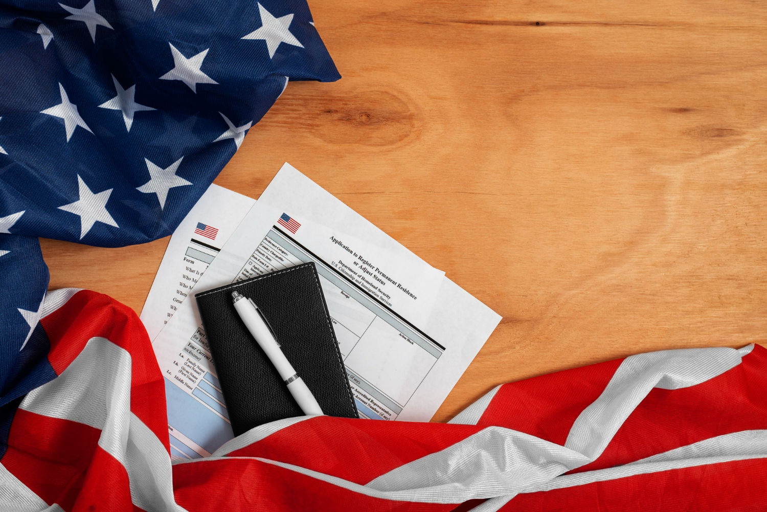 U.S. passport, green card, and Statue of Liberty souvenir on American flag - Immigration and Visa Process.