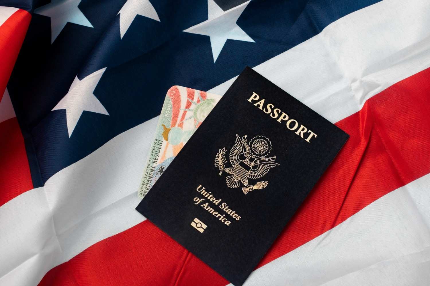 US passport and green card on American flag – symbolizing US visa refusal and waivers.