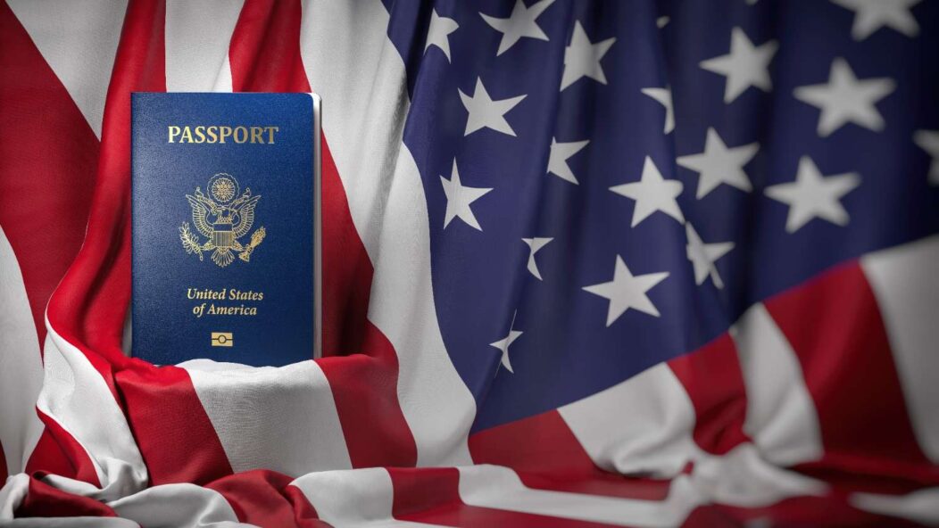 Green card, U.S. passport, and Statue of Liberty on an American flag representing U.S. immigration and Form I-9 updates.