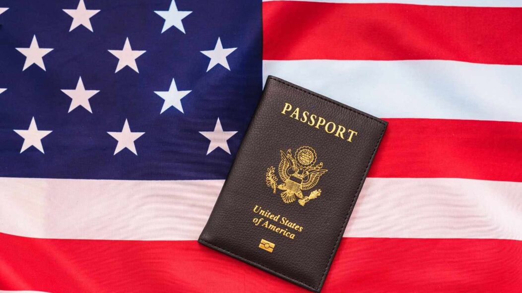 US passport and green card on American flag – symbolizing US visa refusal and waivers.