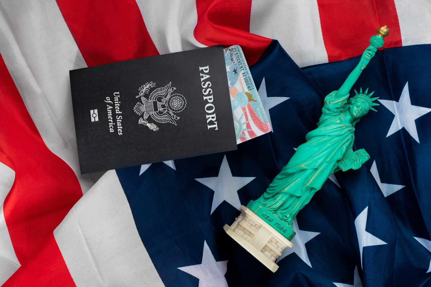 Green card, U.S. passport, and Statue of Liberty on an American flag representing U.S. immigration and Form I-9 updates.
