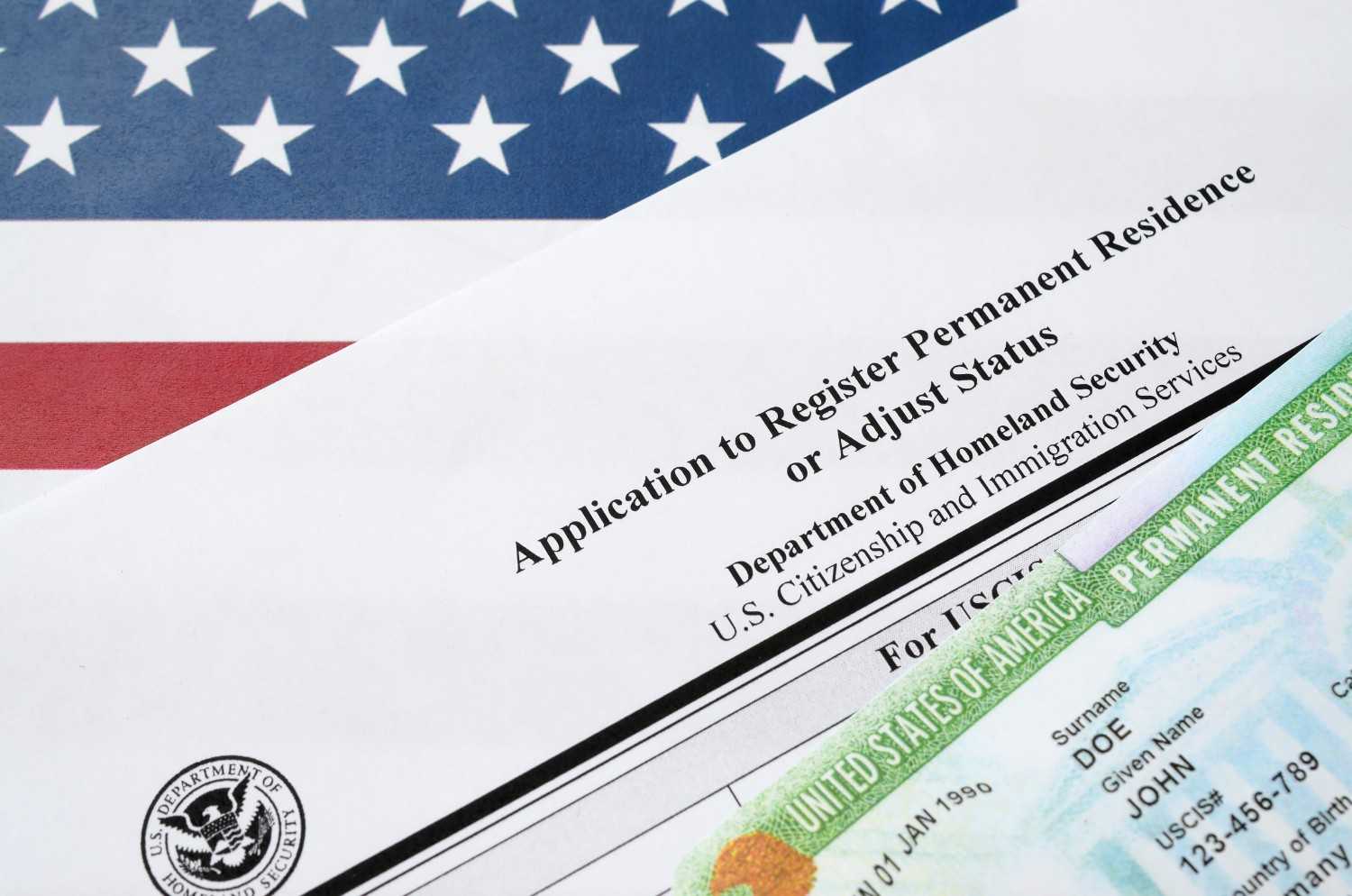 U.S. passport, green card, and Statue of Liberty souvenir on American flag - Immigration and Visa Process.