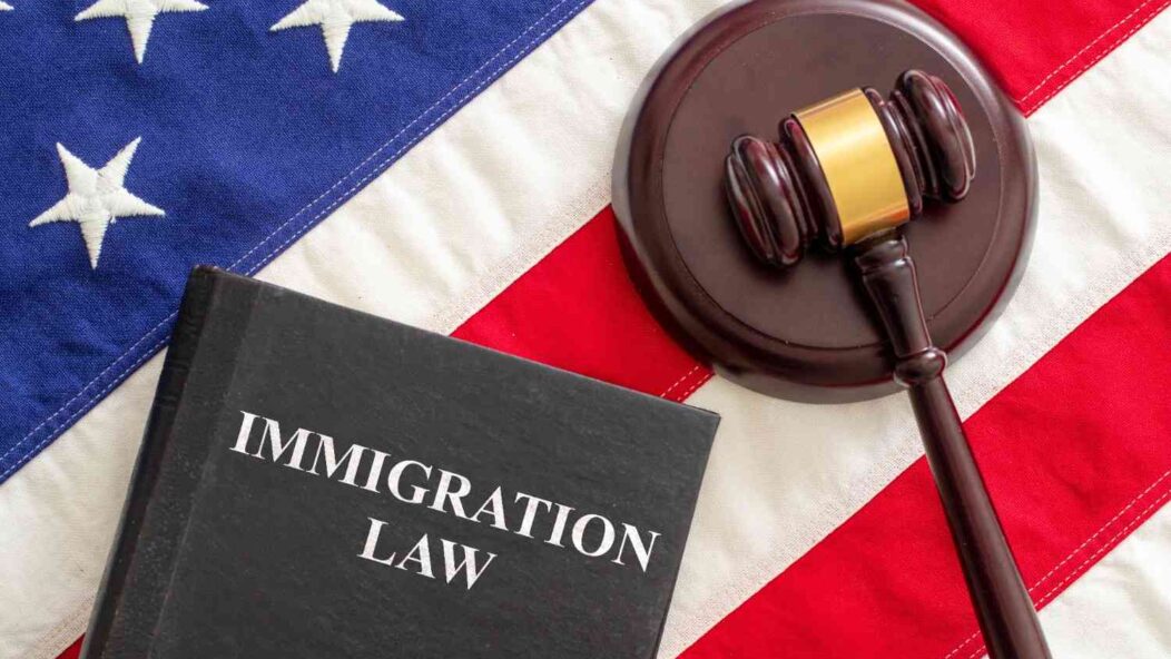 Immigration law book and judge gavel on American flag representing U.S. immigration legal aid and attorney services