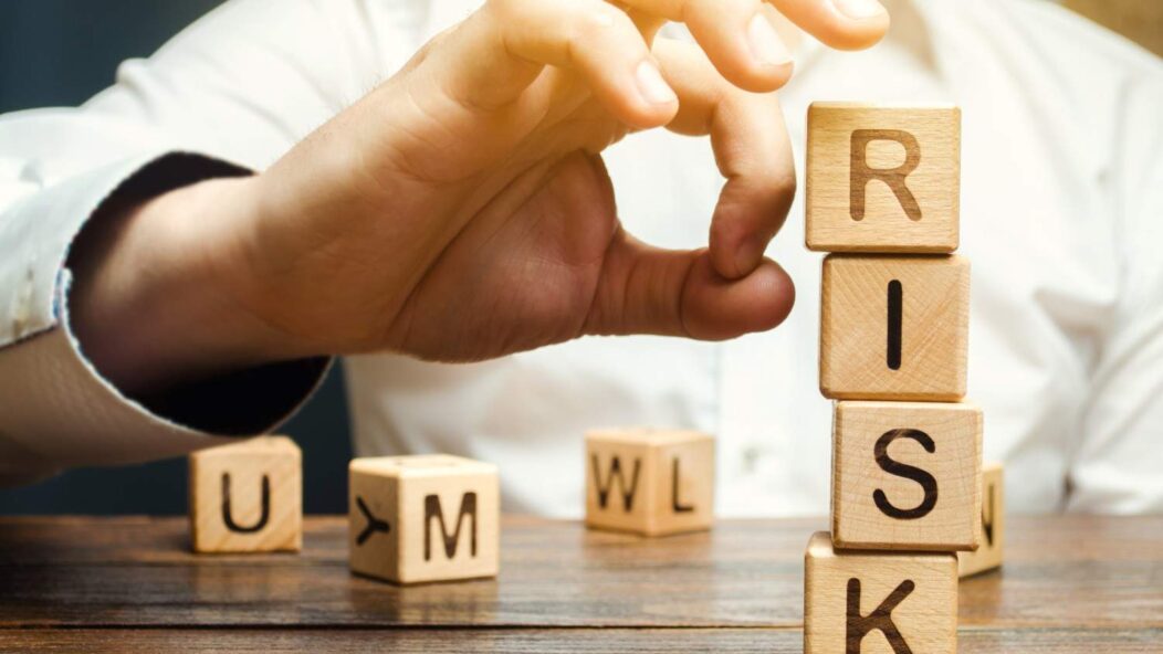 Hand removing blocks with the word 'RISK' to represent risk management in business decisions