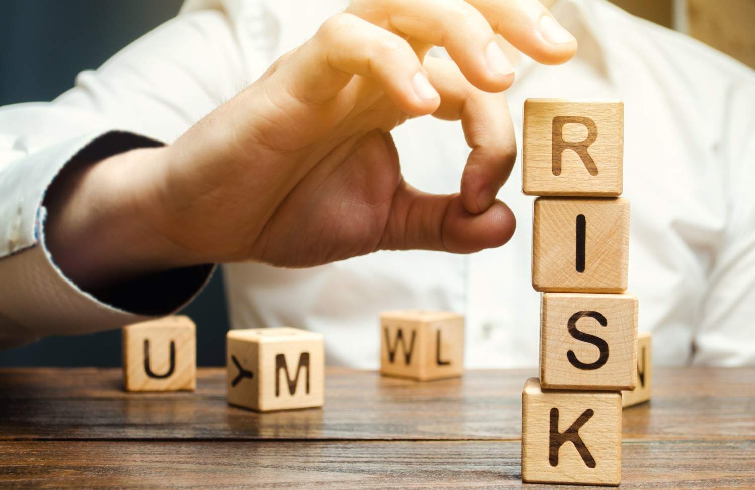 Hand removing blocks with the word 'RISK' to represent risk management in business decisions