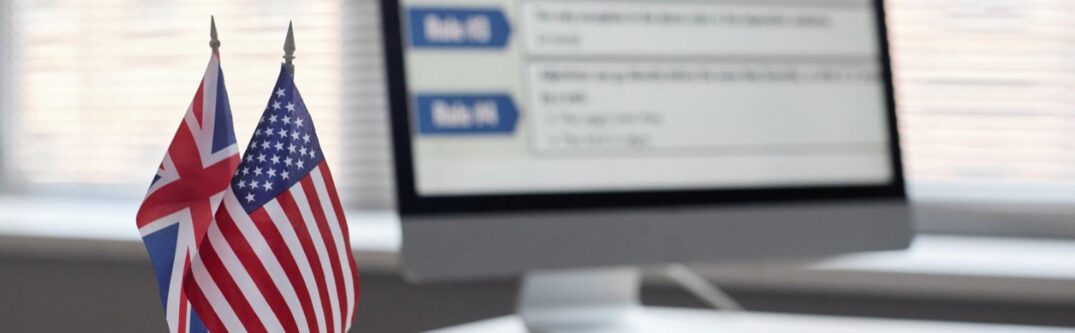 British and American flags on a desk with computer screen in background during FDNS H-1B visa compliance site visit