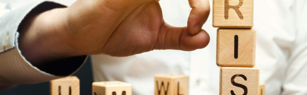 Hand removing blocks with the word 'RISK' to represent risk management in business decisions