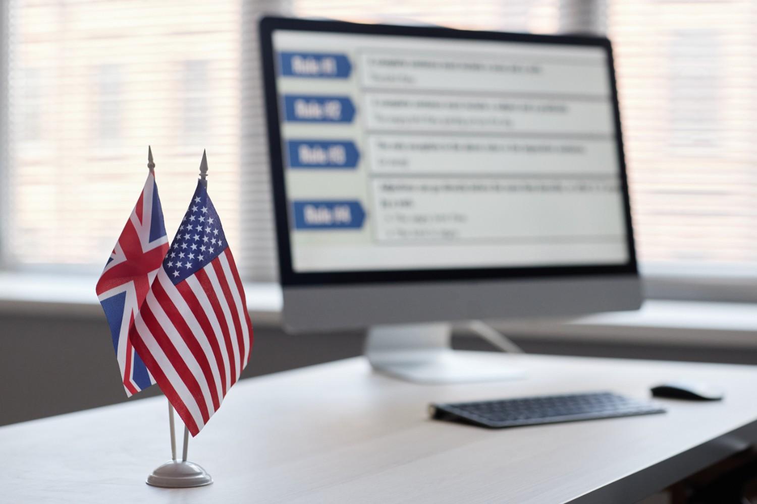 British and American flags on a desk with computer screen in background during FDNS H-1B visa compliance site visit