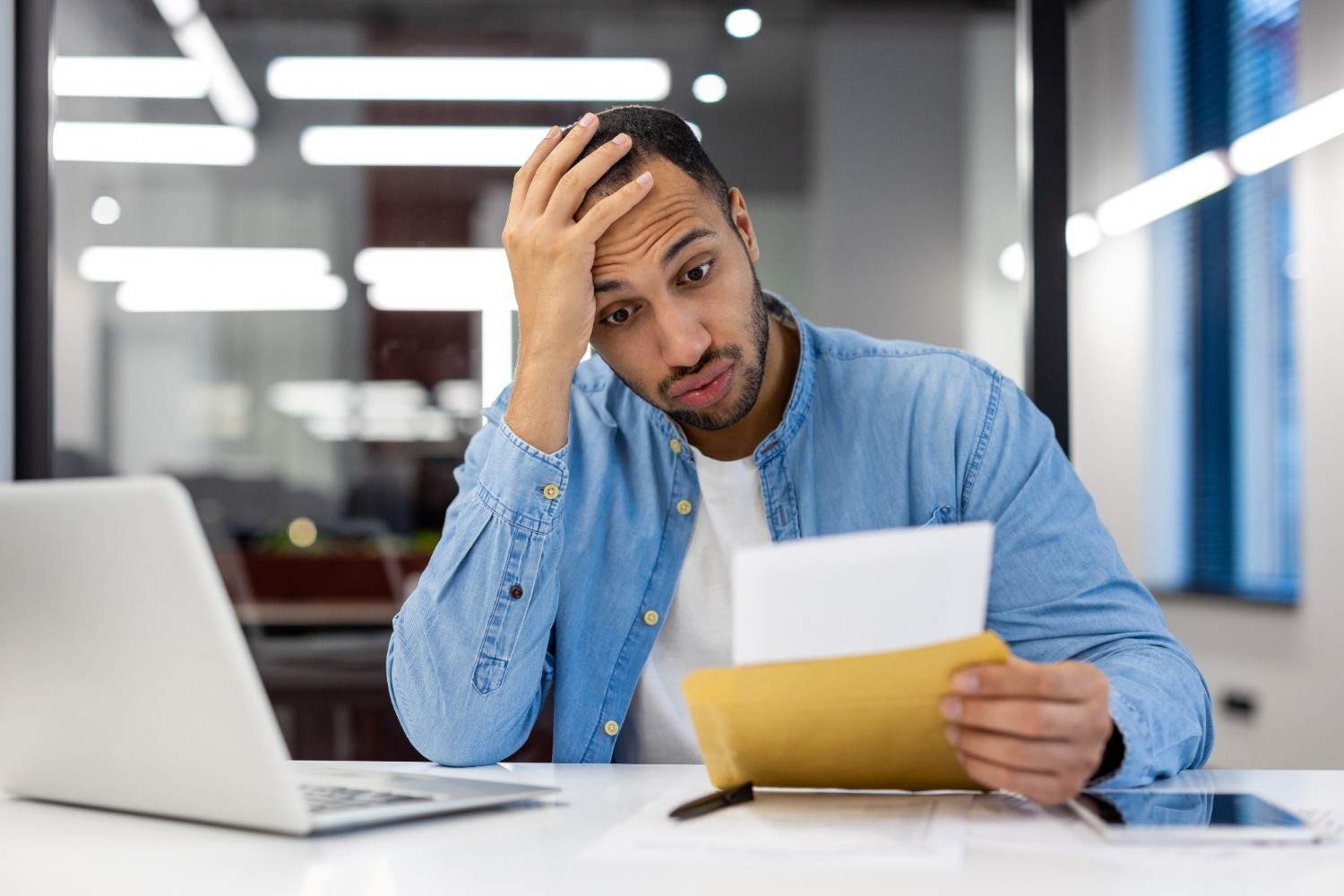Frustrated man reading immigration rejection letter due to paperwork error, highlighting the risk of application mistakes.